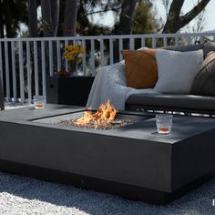 a fire pit sitting on top of a patio next to a couch and coffee table