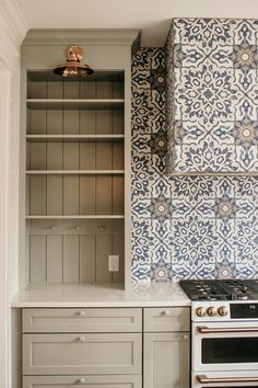 a stove top oven sitting inside of a kitchen next to a wall covered in tile