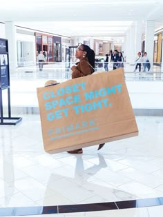 a woman carrying a shopping bag while talking on her cell phone in an airport lobby