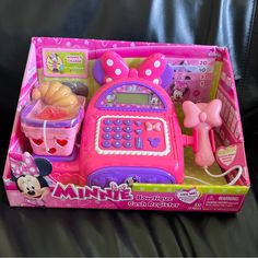 a pink toy cell phone with minnie mouse and other toys in it's box