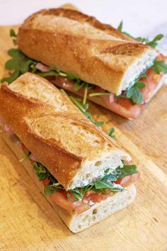 two halves of a sandwich sitting on top of a cutting board next to each other