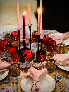 the table is set with candles, plates and napkins