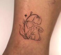 a small tattoo on the ankle of a woman's leg with a rabbit and flower