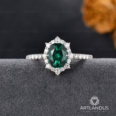 an oval cut green tourmaline surrounded by white diamonds on a black velvet cushion