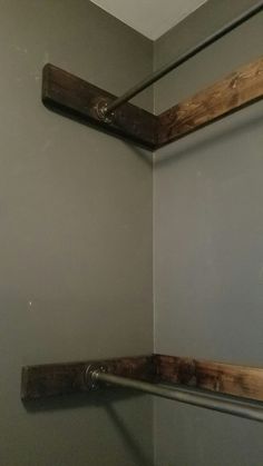 the corner of a bathroom with two wooden shelves