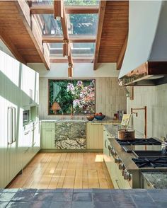 a kitchen with wood flooring and green cabinetry has a skylight above the stove