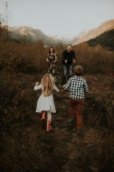 two children and their parents are walking in the woods with mountains in the back ground