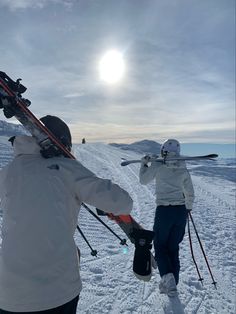 two people with skis walking in the snow