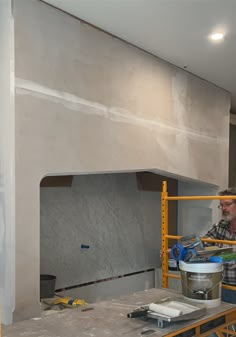 two men are working on a wall in a room that is being remodeled with yellow scaffolding