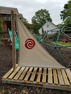 a sailboat is sitting on top of some wood pallets in a playground area