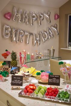 a table filled with lots of different types of food and balloons that say happy birthday