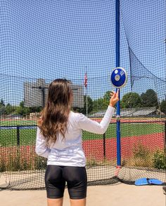 a woman holding a blue frisbee in front of a fenced off area