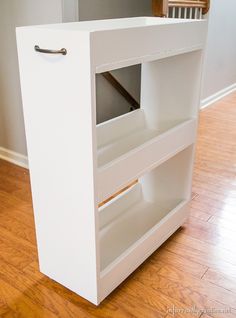 a white book shelf sitting on top of a hard wood floor