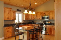 a kitchen with wooden cabinets and black counter tops next to an island in the middle