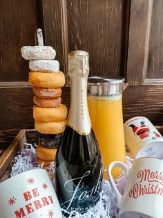 a bottle of champagne, two mugs and some donuts