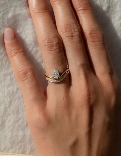 a woman's hand wearing a gold ring with a heart shaped diamond on it