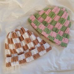 two crocheted hats laying on top of a bed