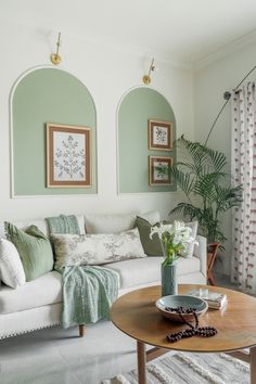 a living room with green walls and white furniture in the corner, along with potted plants