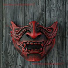 a red mask hanging on the side of a wooden wall