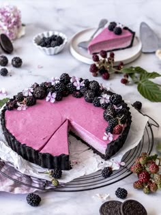 a pink and black cheesecake with berries on top