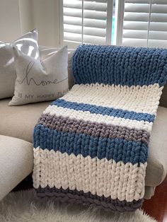 a crocheted blanket sitting on top of a couch next to pillows and a pillow