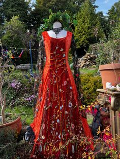 a red dress is on display in a garden