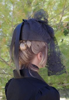 Enter as a lady of mystery with this most-refined piece of mourning clothing. You will know for sure that you are following the highest society standards for the occasion when you place this hat on your head. Discreetly shield your face with the delicate lace veil or attach it to the top of the hat when the appropriate moment presents itself. Made of the highest quality materials, the hat includes a thick black ribbon in the back and feathers and a bow in front. Perfect for macabre-themed events Black Curved Brim Costume Hat For Church, Black Costume Hat With Curved Brim For Church, Black Costume Hat For Church With Curved Brim, Black Costume Hats For Church, Black Costume Hats And Headpieces For Church, Elegant Black Hat For Costume, Elegant Black Costume Hat, Vintage Black Costume Accessories For Wedding, Elegant High Crown Headpiece For Costume