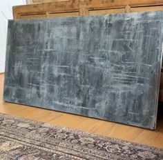 a large black chalkboard sitting on top of a wooden floor next to a rug