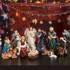 a group of christmas figurines sitting on top of a table next to a tree