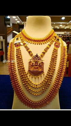 an elaborate gold necklace and earring set on display in a jewelry store, with people looking at it