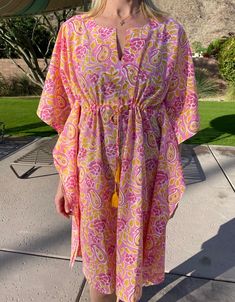 Our beautiful block-print coverups are printed by hand by textile artisans in Jaipur India. The "Mirabelle" short coverup is made in a lightweight organic cotton and features a pink floral and paisley design on our classic kaftan shape with notch neckline, drawstring detail to adjust the fit, cotton tassel trim and side slits for an easy-breezy look. Wear it as a dress over your favourite swimwear to keep cool and covered up or as comfy lounge wear. You may find some small marks on the fabric, these are tiny dye droplets and a normal feature of the wood block printing process signifying the handmade nature of these products. SIZE AND FIT INFORMATION One size fits all: UK dress size 10-16 (US sizes 6-12) Model is 5' 8" UK dress size 12 (US size 8) and wears one size Length: 95cm (37.5 inche Pink Block Print, Tassel Outfit, Cotton Kaftan Dress, Comfy Lounge Wear, Maxi Kaftan, Comfy Lounge, Cotton Kaftan, Women's Cover Up, Indian Cotton