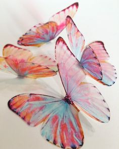 four pink and blue butterflies sitting on top of a white countertop next to each other