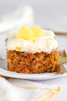 a piece of carrot cake with white frosting on a plate next to a fork