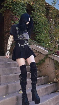 a woman with black hair and boots standing on some steps