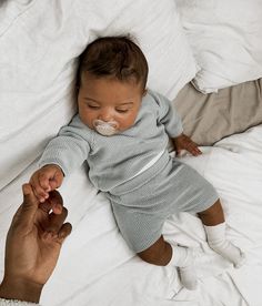 a baby laying on top of a bed with a pacifier in it's mouth