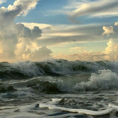 an ocean scene with waves crashing on the shore and clouds in the sky above it