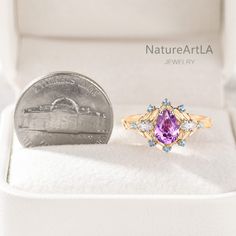 a purple ring sitting on top of a white box next to a quarter dollar coin