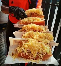 three hot dogs covered in sauerkraut and shredded cheese