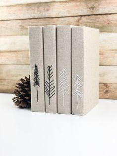 three books with pine cones on them sitting next to each other