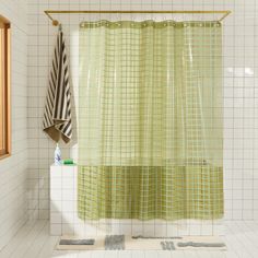 a green shower curtain in a white tiled bathroom