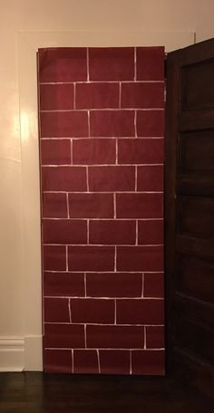 a red brick wall in the corner of a room with a wooden door and dark wood floor