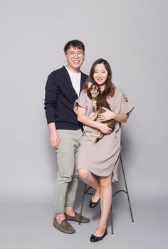 a man and woman pose for a photo while holding a small dog in their arms