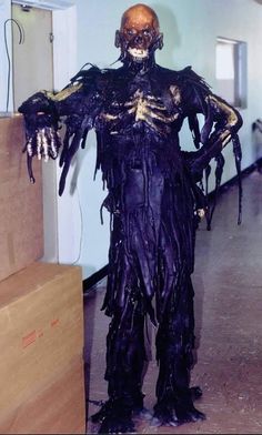 a man dressed up as a skeleton in a room with boxes on the floor and walls