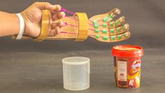 a person's hand is holding something in front of a plastic cup and container