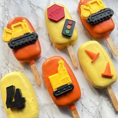 four popsicles with construction themed frosting on them sitting on a marble countertop