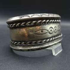 "VINTAGE NAVAJO BRACELET DESCRIPTION: This old hand wrought Navajo cuff bracelet features intricate designs. The hand-stamped edges are carinated, and thick twisted silver wire serves as an additional border. From the Frank Kinsel collection, this collectible bracelet will be a cherished addition to your collection of the very finest vintage Native American jewelry. MEASUREMENTS: Interior of the cuff measures 5 1/2\" with an additional 1 1/8\" slightly adjustable gap. Total circumference: 6 5/8\ Antique Silver Cuff Bangle Bracelet, Antique Silver Bangle Cuff Bracelet, Vintage Antique Silver Cuff Bracelet For Ceremonial Occasions, Vintage Adjustable Jewelry, Heavy Adjustable Vintage Jewelry, Bohemian Stamped Bracelets For Wedding, Bohemian Stamped Bracelet For Wedding, Antique Adjustable Cuff Bracelet With Intricate Design, Adjustable Stamped Antique Silver Bracelet