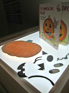 an illuminated display case with two pumpkins and faces on the front, one has a card in it