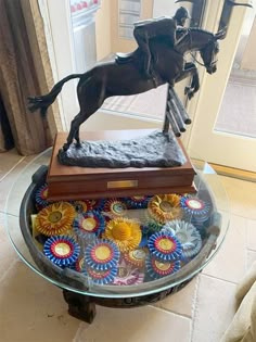 a glass table topped with a statue of a horse and rider on top of it