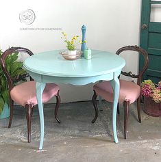 the table and chairs are painted blue with pink upholstered fabric, along with potted plants