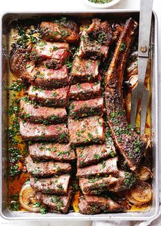 a pan filled with steak and vegetables next to a bowl of sauce on the side